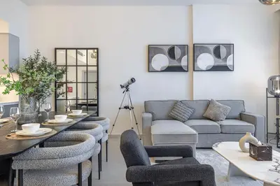 a living room with a couch and a table and chairs at Mahogany 8 - 4BR 14PAX - Burj Khalifa View Central in Dubai