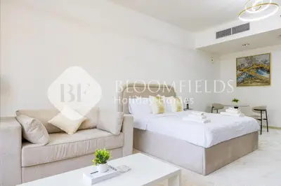 a white living room with a bed and a couch at Bloomfields Luxurious Stu in Mulberry 1 Emirates in Dubai