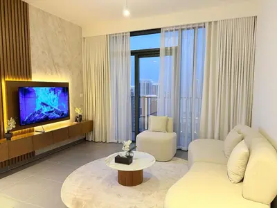 a living room with a white couch and a television at Comfortable 2BR Stay with Sea View in Dubai