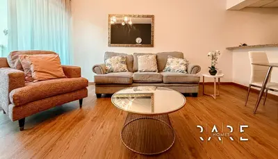 a living room with a couch and a table at Rare Holiday Homes - Near Metro Station - Greens - Al Arta - R215 in Dubai