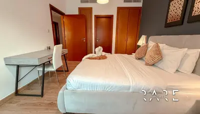 a bedroom with a bed with a desk and a bed sidx sidx sidx at Rare Holiday Homes - Near Metro Station - Greens - Al Arta - R215 in Dubai
