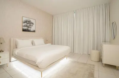a white bedroom with a white bed and a window at Granduer 1 BR in Windsor Manor Canal Front Living With Burj Views in Dubai