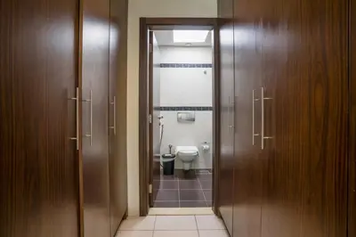 a bathroom with two wooden doors and a toilet at Granduer 1 BR in Windsor Manor Canal Front Living With Burj Views in Dubai
