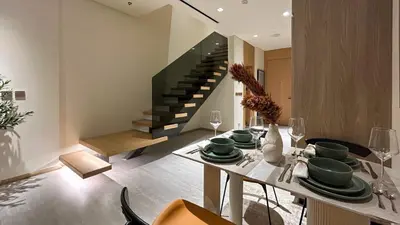 a dining room with a table and a staircase at Bespoke Holiday Homes - Stylish 1BR Penthouse in The Autograph in Dubai