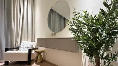 a mirror and a chair and a plant in a room at Bespoke Holiday Homes - Stylish 1BR Penthouse in The Autograph in Dubai