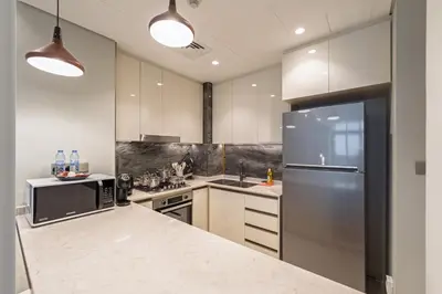 a kitchen with white cabinets and a refrigerator at Contemporary 1BR Prime Location with Parking in Dubai