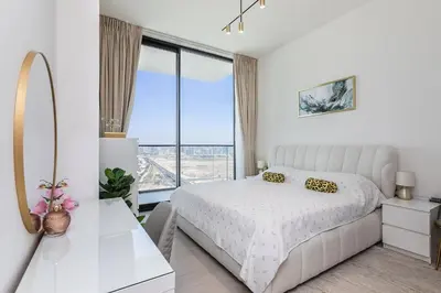 a white bedroom with a bed and a large window at Celestial View 1BR apartment in JVC in Dubai
