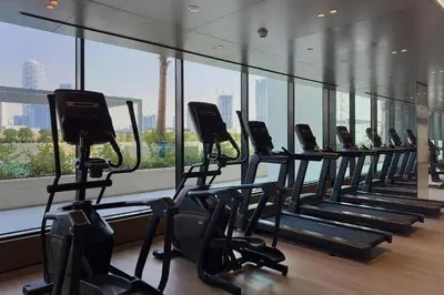 a row of exercise bikes in a gym with a large window at Celestial View 1BR apartment in JVC in Dubai