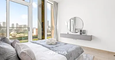a bedroom with a bed and a mirror and a window at Elegant Luxury 1BR - Modern Design - JVC in Dubai