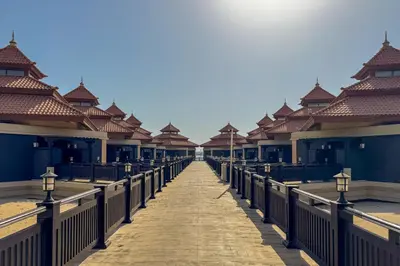 a wooden walkway leading to a row of buildings at Homely 1 Bedroom on Palm Jumeirah with private beach in Dubai