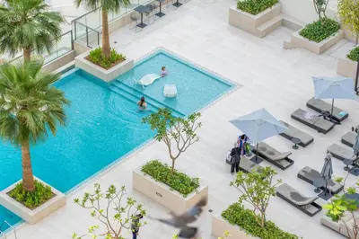 an overhead view of a swimming pool with palm trees and chairs at LUX New Studio With 2 Double Beds in Downtown Dubai, Pool View, Free Parking in Dubai