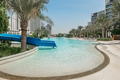a pool with a slide in a resort with palm trees at qua Serenity Poolside with Community Views in Dubai