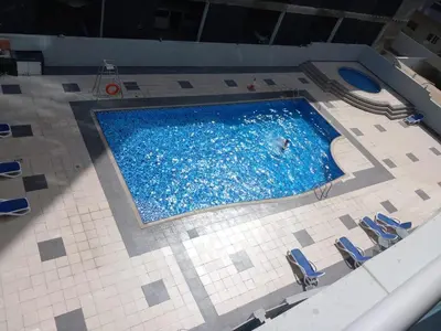 a swimming pool with chairs and a person in the water at Diamond Studio Marina in Dubai