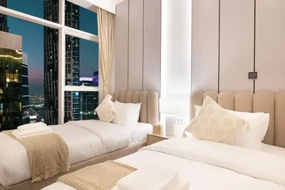 two beds in a room with a view of a city at Mahogany 10 - 2BR 8 PAX - Infinity Pool & Modern in Dubai