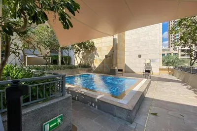 a swimming pool with an umbrella in a courtyard at City View Studio, Minutes Away from Dubai Opera, Burj Khalifa and Dubai Mall, Claren Tower 2, Downtown Dubai by Deluxe Holiday Homes in Dubai