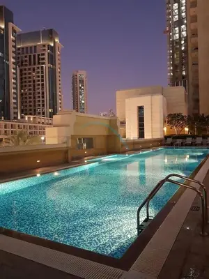 a large swimming pool in a city at night at City View Studio, Minutes Away from Dubai Opera, Burj Khalifa and Dubai Mall, Claren Tower 2, Downtown Dubai by Deluxe Holiday Homes in Dubai