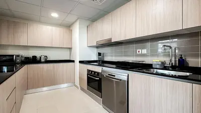 a kitchen with stainless steel appliances and wooden cabinets at Trophy-Lux Villa w Big Garden & BBQ Grill in Dubai