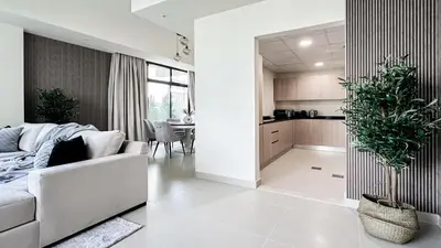 a living room with a white couch and a kitchen at Trophy-Lux Villa w Big Garden & BBQ Grill in Dubai