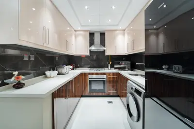 a kitchen with white counters and wooden cabinets at 1BR with Balcony View, Gym, Pool & Kids Play Area in Dubai