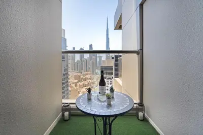 a table with a bottle of wine in a room with a window at 1BR with Balcony View, Gym, Pool & Kids Play Area in Dubai