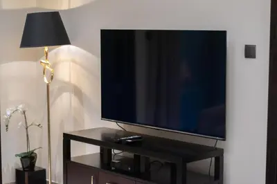 a flat screen tv sitting on a table next to a lamp at 1BR with Balcony View, Gym, Pool & Kids Play Area in Dubai