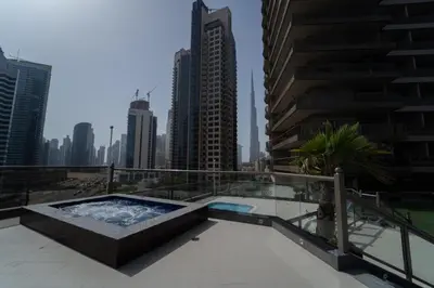 a hot tub on the roof of a building with tall buildings at 1BR with Balcony View, Gym, Pool & Kids Play Area in Dubai