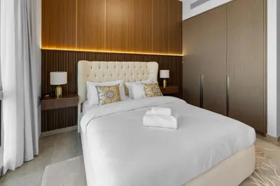 a bedroom with a large white bed with wooden walls at Luxury Stay Just Steps from Dubai Mall 2BR Grande in Dubai