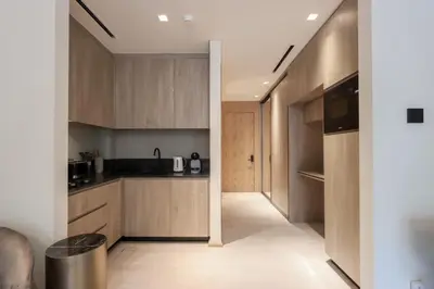 a kitchen with wooden cabinets and a hallway at Livbnb - Stylish Studio in JVC, Near Parks and Shops in Dubai