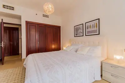 a bedroom with a white bed and a wooden cabinet at Cozy 1BR Apart Downtown Burj Khalifa and Dubai Mall in Dubai