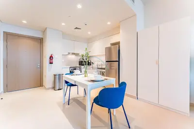 a kitchen with a white table and blue chairs at High-Rise 1BR with Stunning Creek Views,Near to Dubai Creek Tower Viewpoint, Harbour Gate Tower 2, Dubai Creek Harbour by Deluxe Holiday Homes in Dubai