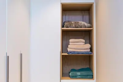 a closet with towels on shelves next to a door at 2BR by Sea, 15min to Dubai Mall in Dubai
