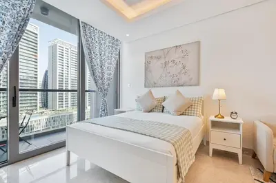 a white bedroom with a bed and a large window at Vibrant&Chic - Studio - 6MN Dubai Mall - Pool&Gym in Dubai
