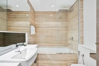 a bathroom with a white sink and a tub at Vibrant&Chic - Studio - 6MN Dubai Mall - Pool&Gym in Dubai