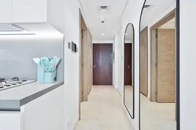a white kitchen with a stove and a hallway at Vibrant&Chic - Studio - 6MN Dubai Mall - Pool&Gym in Dubai
