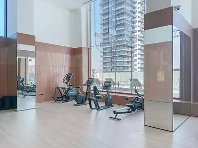 a gym with several treadmills and a large window at Binghatti House - Two Bedroom with Private Pool in Dubai