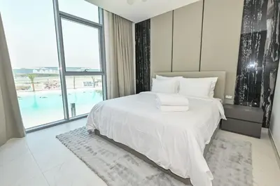 a bedroom with a white bed and a large window at Chic 2BR Heart of District One in Dubai