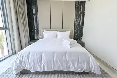 a bedroom with a white bed with white sheets and pillows at Chic 2BR Heart of District One in Dubai