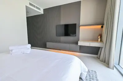a bedroom with a white bed and a flat screen tv at Chic 2BR Heart of District One in Dubai