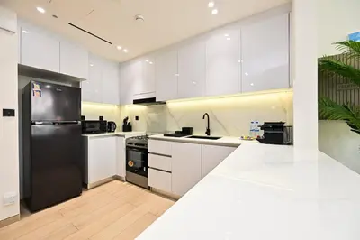 a kitchen with white cabinets and a black refrigerator at Stunning 1 br modern luxury residence at JVC in Dubai