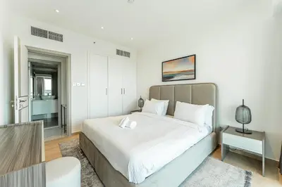 a white bedroom with a large bed and a table at HAVN - Upgraded 1 Bed in 8 Boulevard Walk Downtown in Dubai