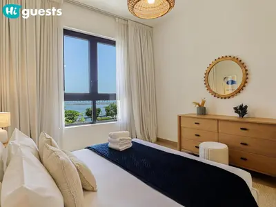 a bedroom with a bed and a window and a dresser at HiGuests - Seaside Serenity 1 BR at Port De La Mer in Dubai