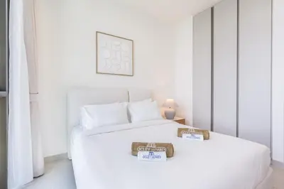 a white bedroom with two beds with price signs on them at Brand New Creek Home with Panoramic Water View in Dubai