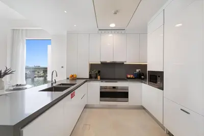 a white kitchen with white cabinets and a window at 2BR Canal Front B3, Waterfront Views in Dubai