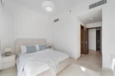 a white bedroom with a white bed with blue pillows at 2BR Canal Front B3, Waterfront Views in Dubai