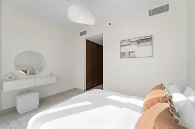 a white bedroom with a bed and a mirror at 2BR Canal Front B3, Canal Views in Dubai