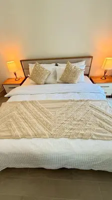 a large white bed with two lamps on two tables at One bedroom Full view Dubai Hills in Dubai