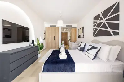 a bedroom with a white bed and a tv at Holiday Boulevard - Stylish Upgraded Studio - Designer Touches in JVC in Dubai