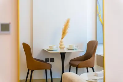 a table with two chairs and a vase on it at Elegant JVC Stay Luxury Amid Nature in Dubai