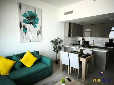 a living room with a green couch and a kitchen at 2BR Sofa Bed Sleep 6 Furjan in Dubai