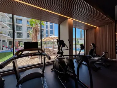 a gym with cardio machines in front of a large window at Luxurious Nature with 5 Star Amenities in JVC in Dubai